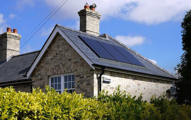 A brick house with solar panels on one slope of its slate roof
